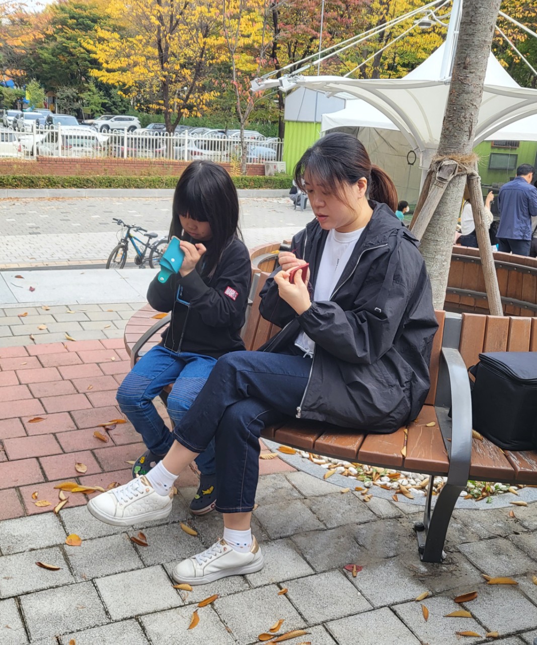 야외 벤치에서 가죽 바느질에 집중하는 체험 참가자
