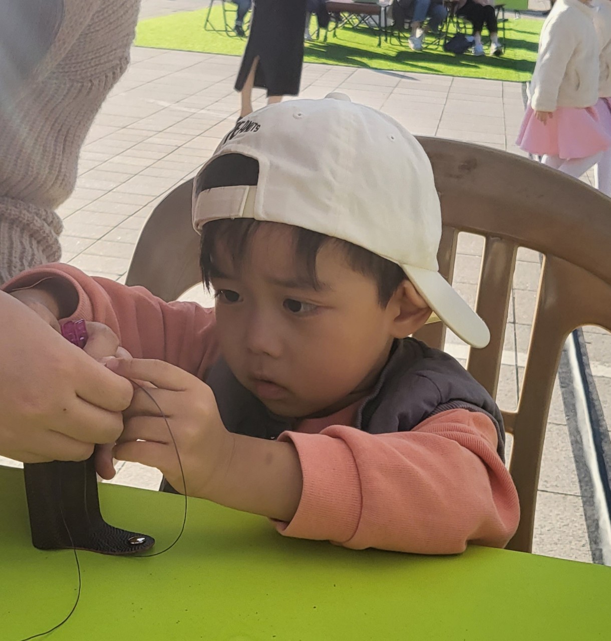 어린 남자아이가 집중해서 가죽 바느질을 하는 모습