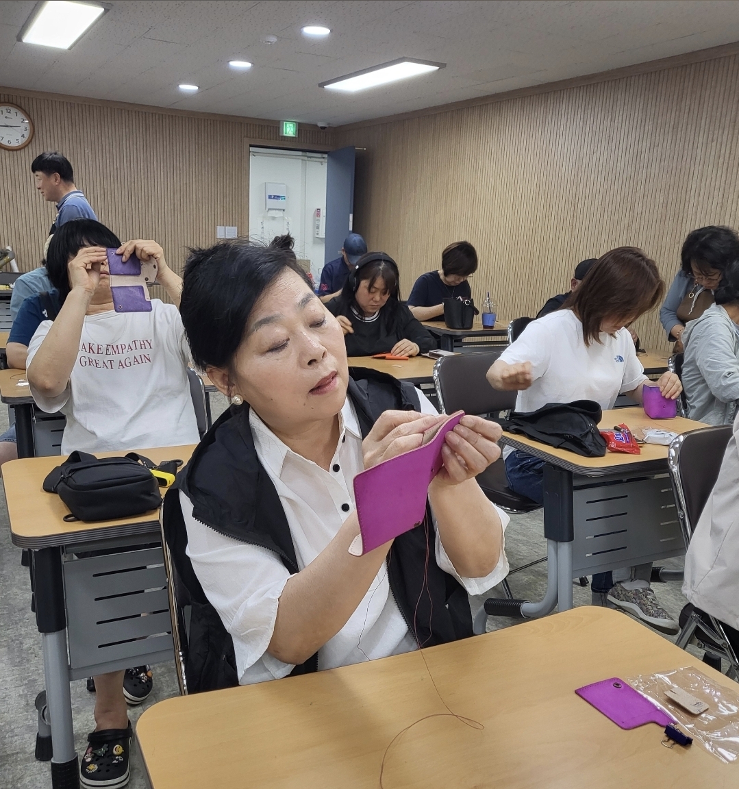 교실에서 여러 수강생들이 가죽공예 카드지갑을 만드는 단체 수업 현장